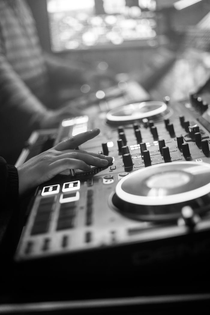 DJ adjusting audio mixer controls during a live music session in a nightclub setting.