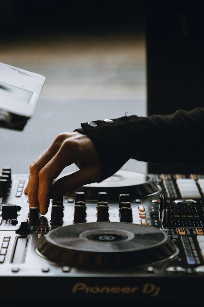 DJ's hand adjusting a mixer, creating vibrant electronic music.